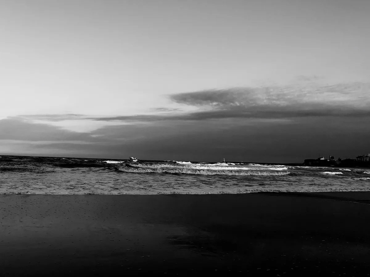 Waves rolling in at dusk off Longsands Beach, in black and white